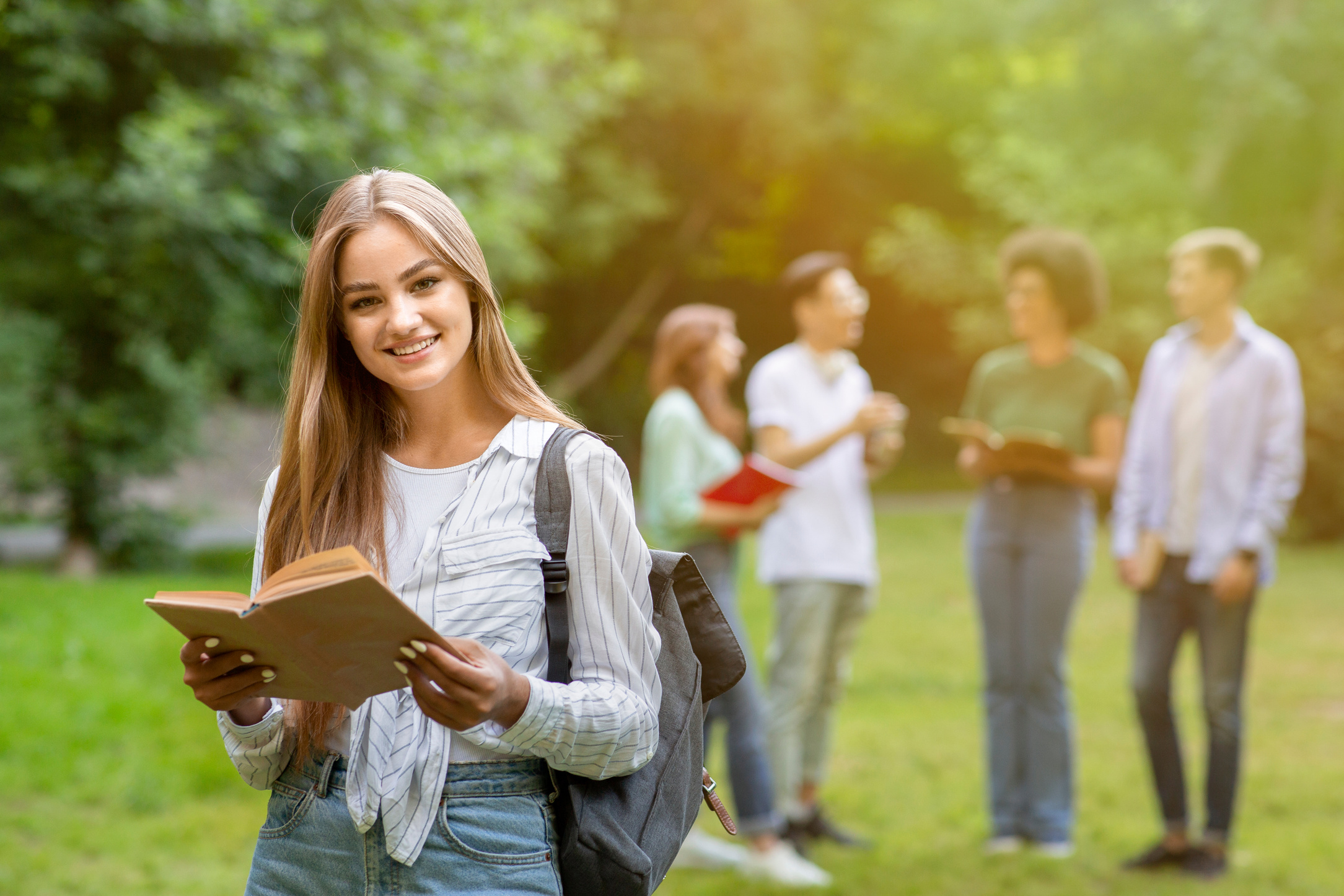 Degree Programs Abroad. Smiling Student With Book Posing Outdoor At Campus
